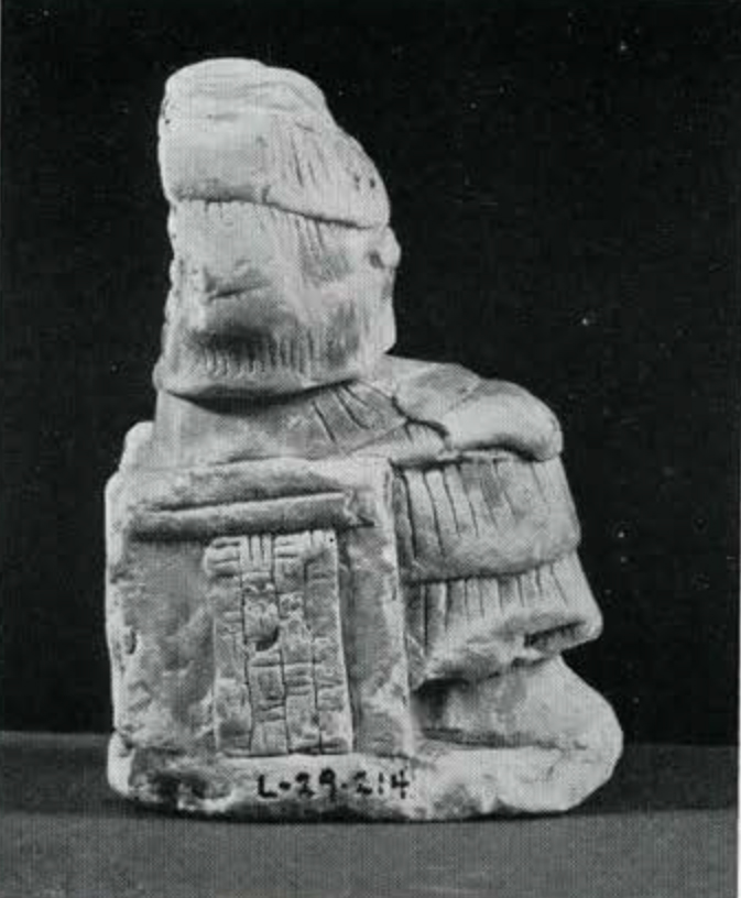Small statuette of a seated figure with tiered garb, head missing