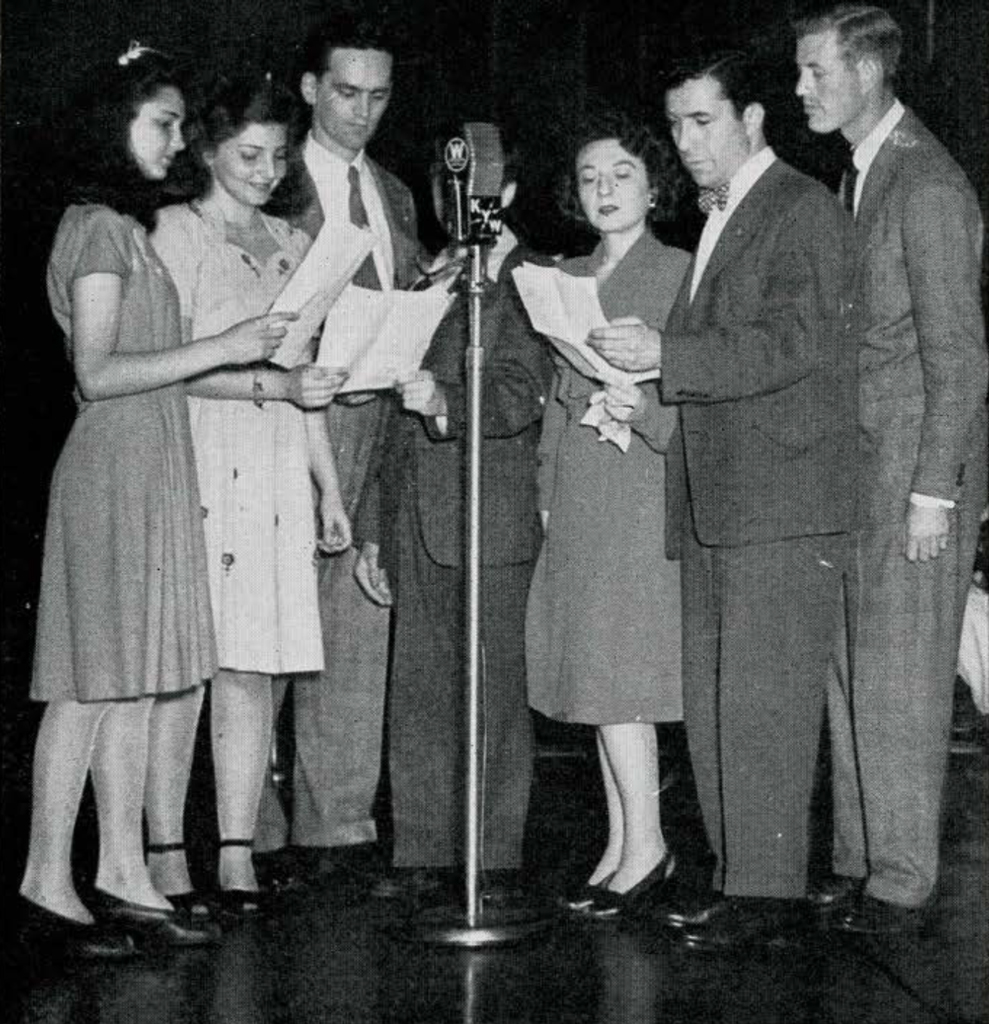 A group of people with sheet music singing into a microphone
