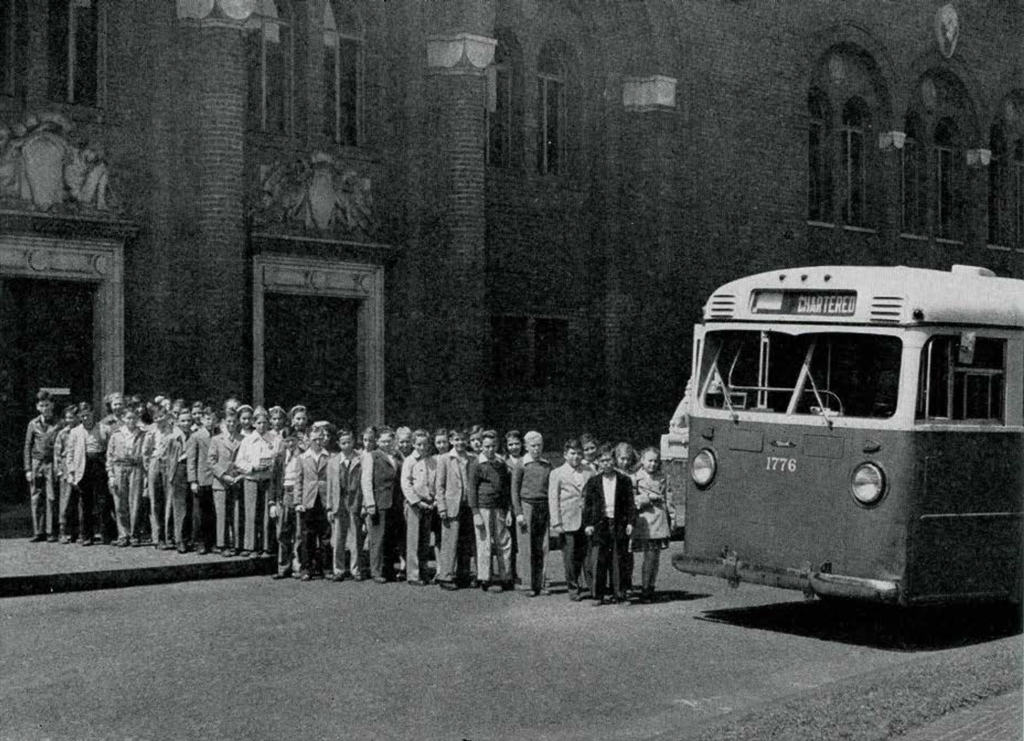 School children in the paved courtyard of the Museum lined up to board a bus