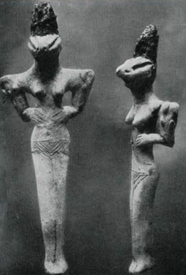 Two female pottery figurines with snake-like heads and tall hair, hands on hips