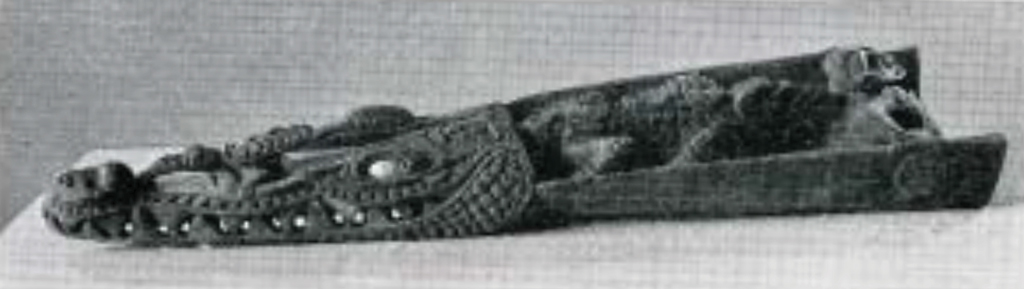Wooden canoe prow carved into the shape of a crocodile head in high relief.