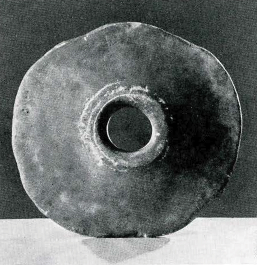 Flat stone disc with a hole in the middle.