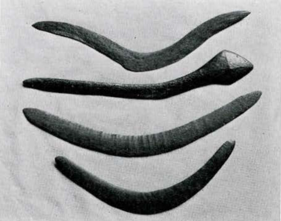 Four boomerangs, one of which has one handle carved into a diamond shape.