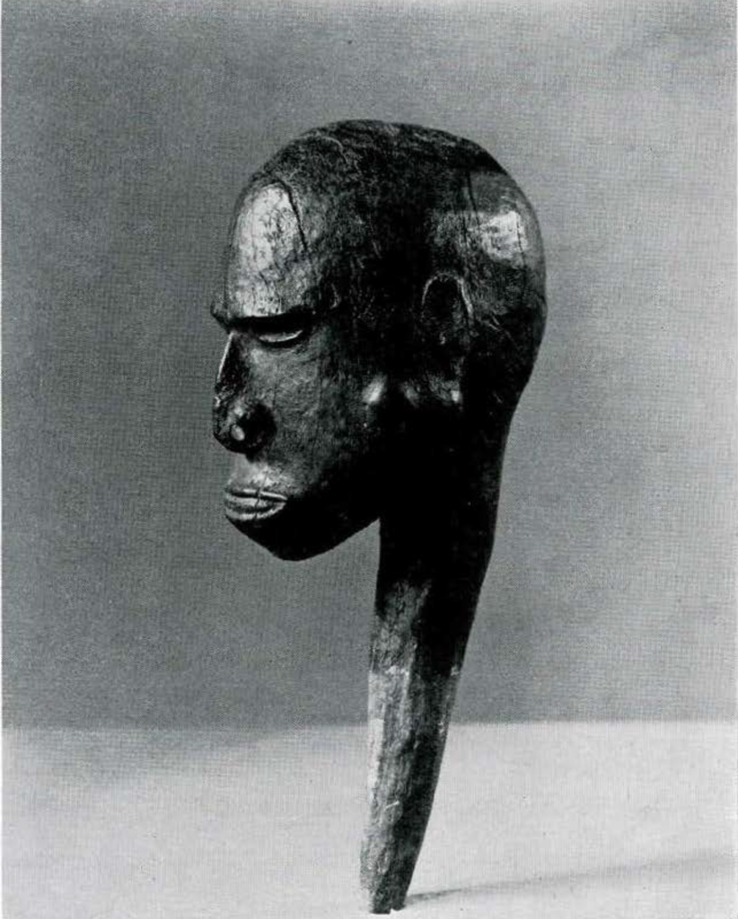 A wooden stopper carved in the shape of a human head.