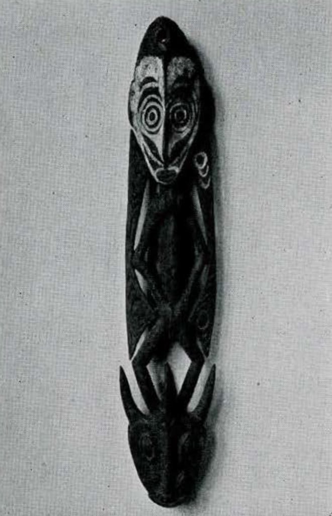 A wooden supsension hook carved in the shape of a man standing on a pig head.