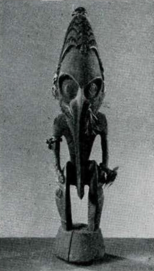 Wood figure of a standing person in a mask with a long hooked beak.