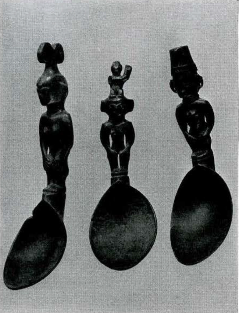 Three wooden spoons with the handles carved into standing figures, each with a different head ornament.