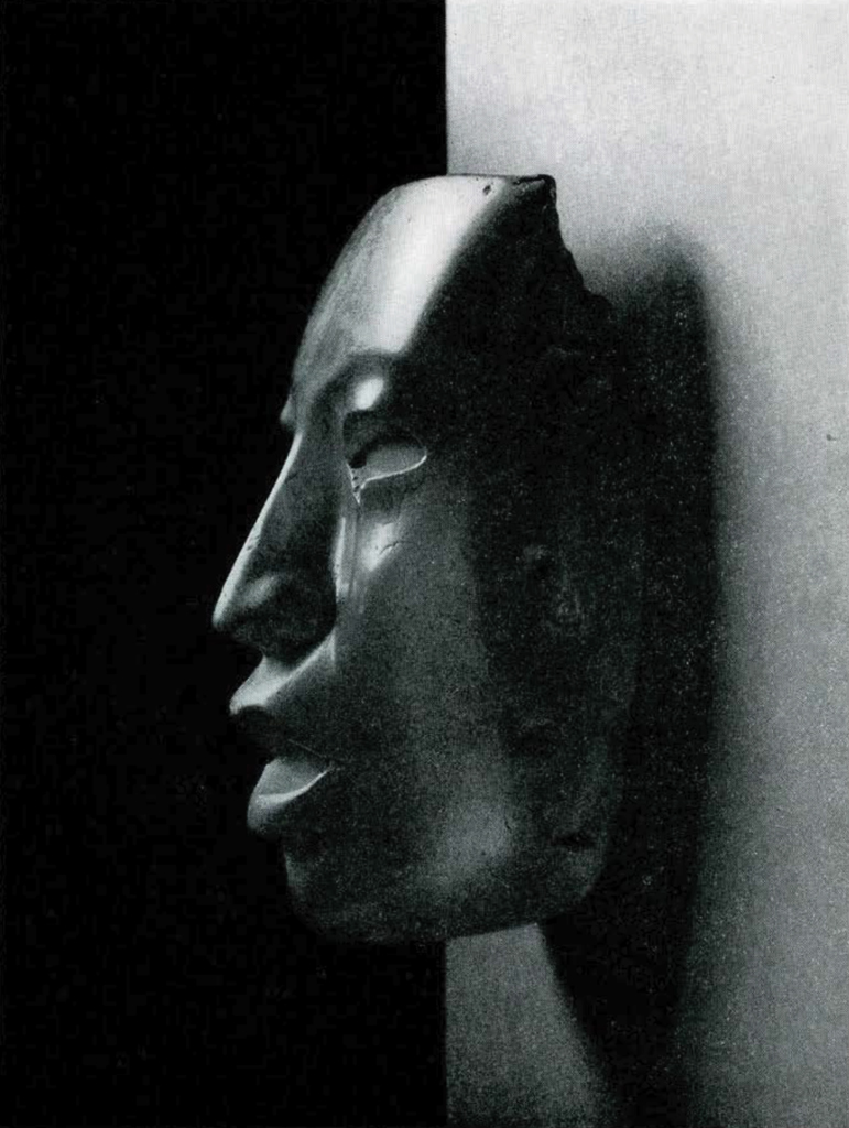 A mask made from semi-translucent travertine, seen from the side, lips slightly parted.