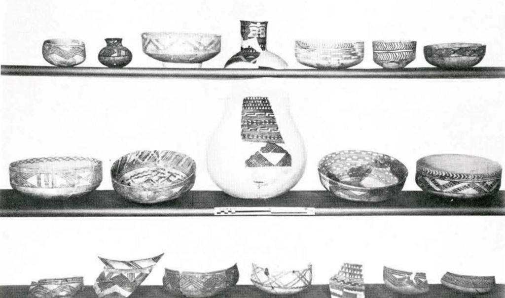 Three shelves of painted pottery, mostly shallow bowls.