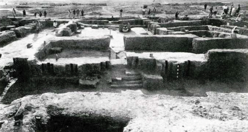 View of the excavated foundations of the main temple at Harmal, workers in the background.