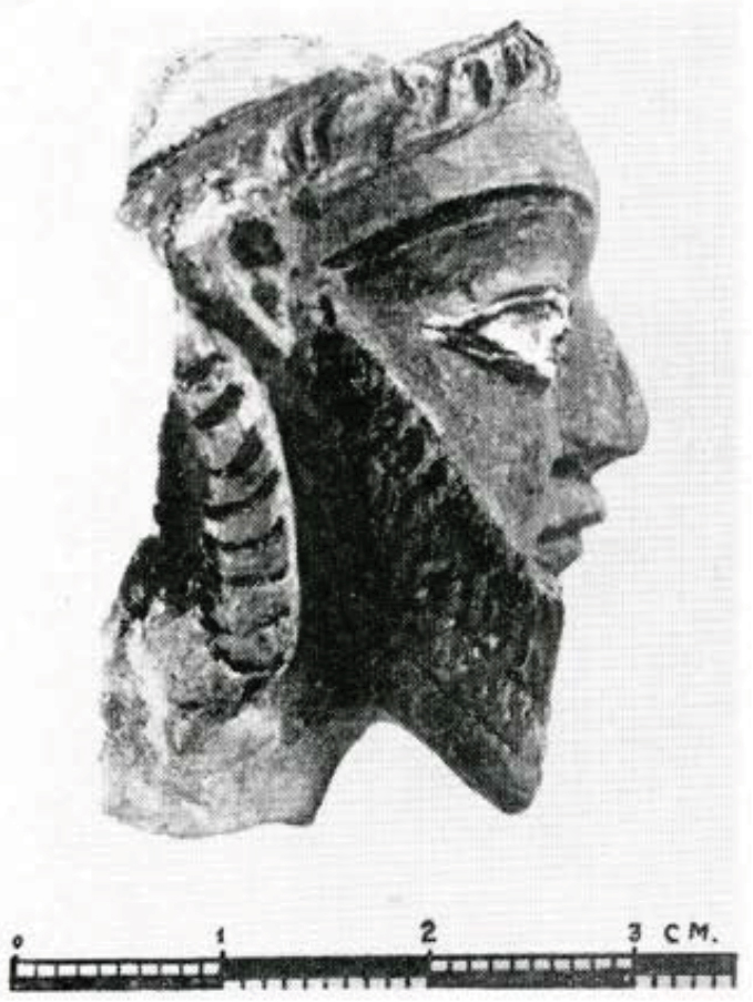 A painted terra cotta head of a man with a bear and headpiece, seen in profile.