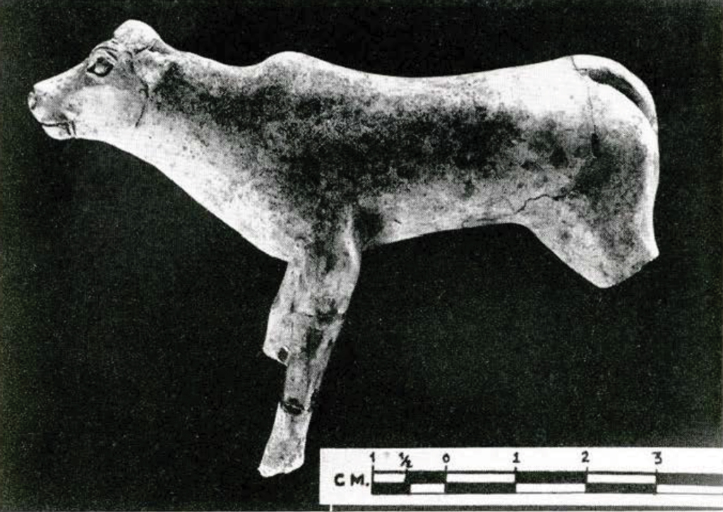 Terra cotta figurine of a cow, missing back legs.