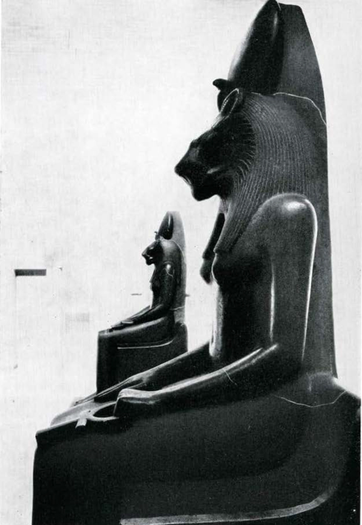 Side view of two black statues of seated lion headed Sakhmet.