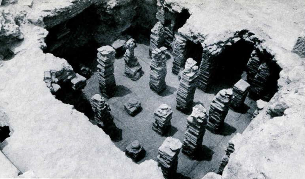 Stone hypocaust pillars seen through a hole in the floor.