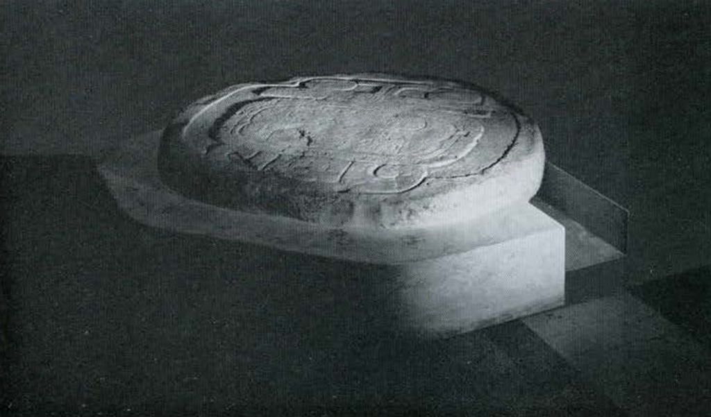 A round stone altar with a giant glyph carved into it.