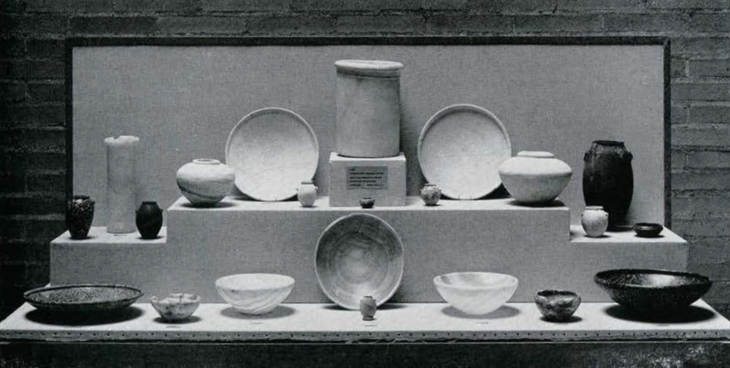 An assortment of pottery displayed in an exhibition case, featuring bowls and vases in various sizes and shapes.