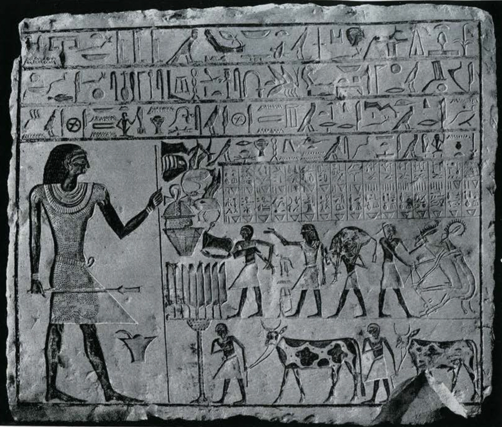 Funerary Stela with brightly colored painting carved in sunk relief, the deceased is shown before piles of offerings and offering bearers bringing different types of meat and animals with many lines of inscriptions.