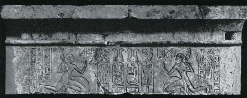A lintel with a carving of two mirrored individuals kneeling with inscriptions surrounding them.