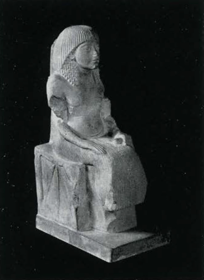 Statue depicting a seated man wearing an elaborate wig, long pleated kilt.