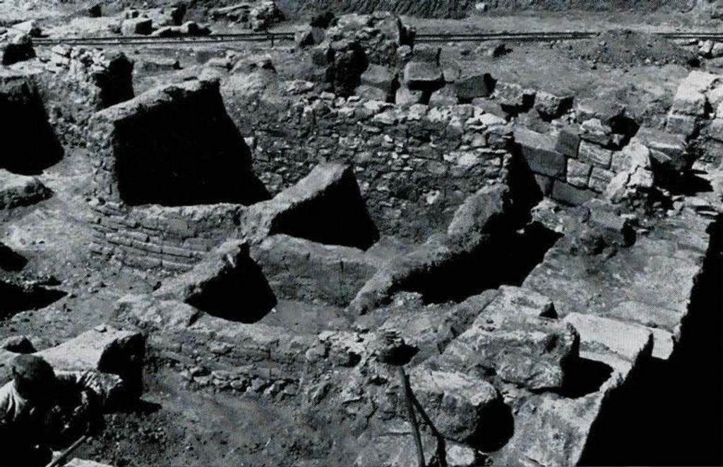 Excavated building foundations made of stone and remains of brick walls.