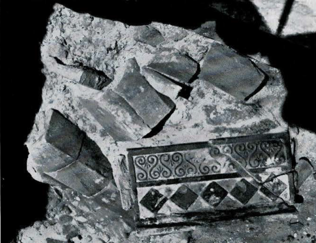 A tile with diamon pattern and curliques, and roof tiles.