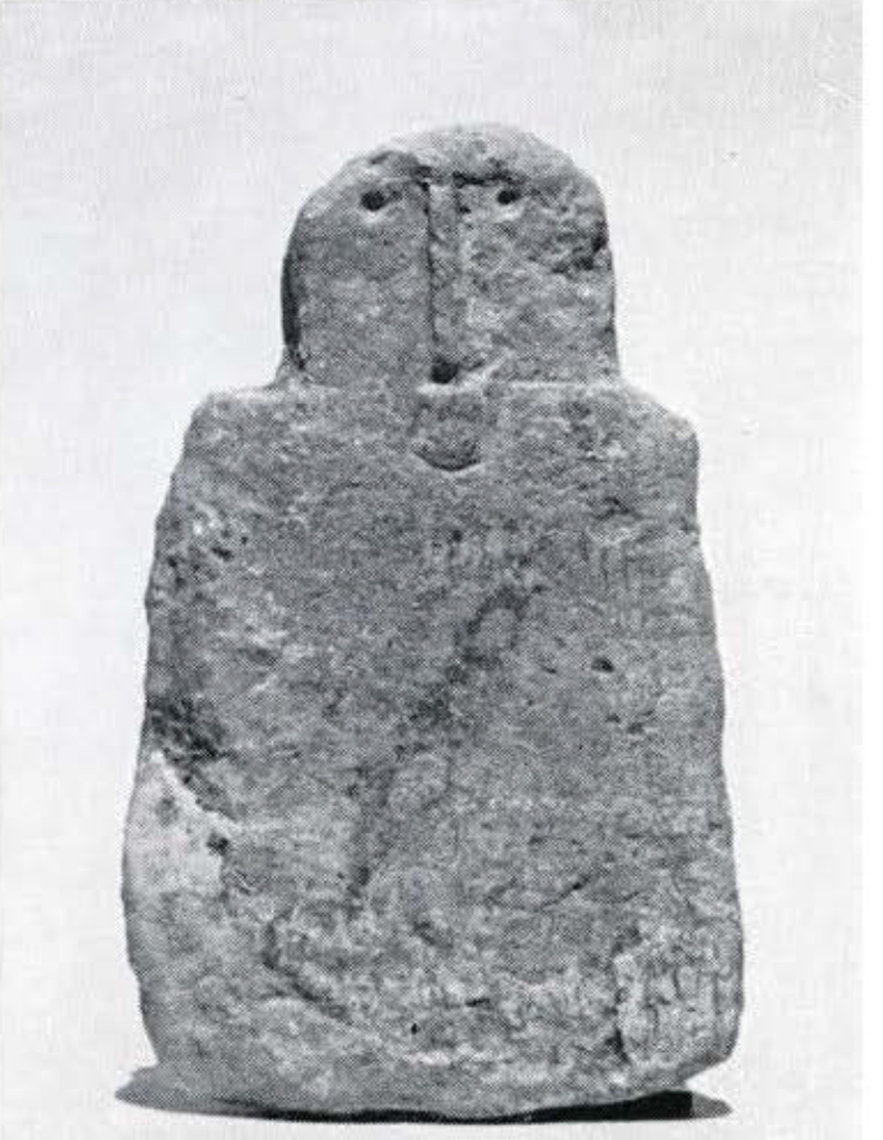 A small stone crudely carved into a rectangle with a rounded face at one end.