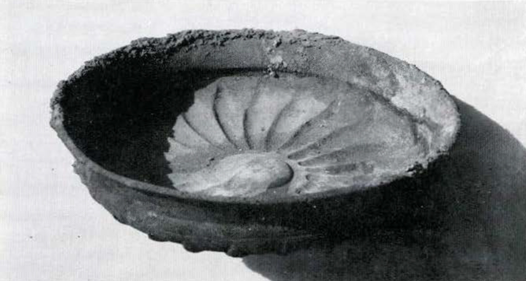 A shallow fluted bowl, crusted over.