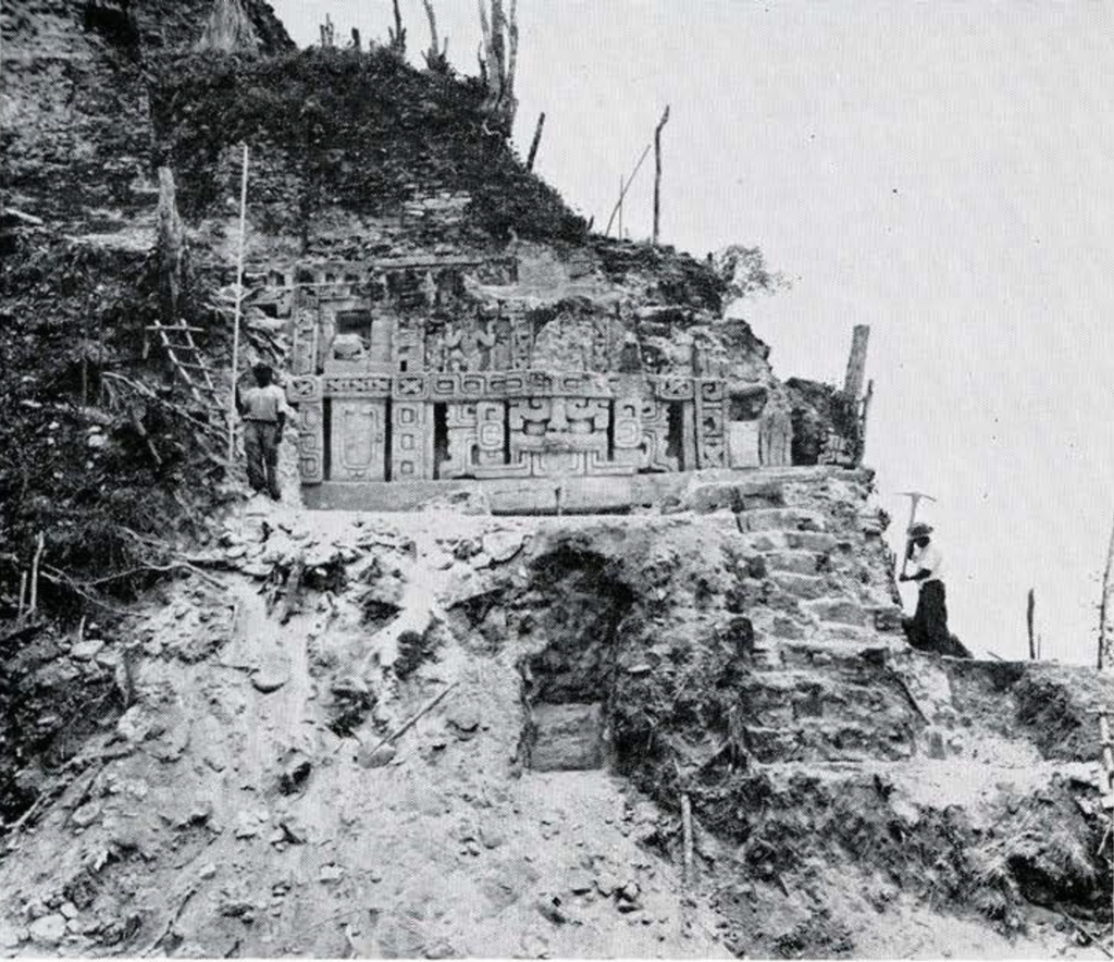 An excavated structure in the side of a hill, showing a stucco façade.