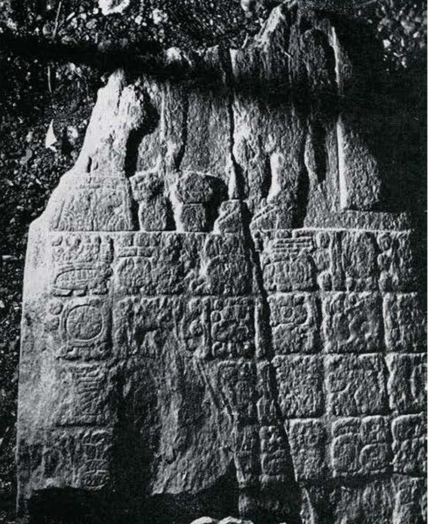 A fragment of a stela broken at the top, with a four by six grid of square carvings.