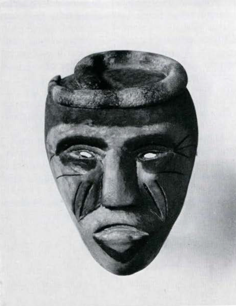 A wooden mask with incised wrinkles on the cheeks and outer eye corners, a snake coiled on top.