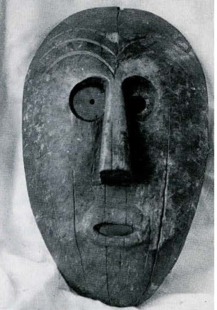 A wood mask with a wrinkled forehead and close set eyes, open mouth.
