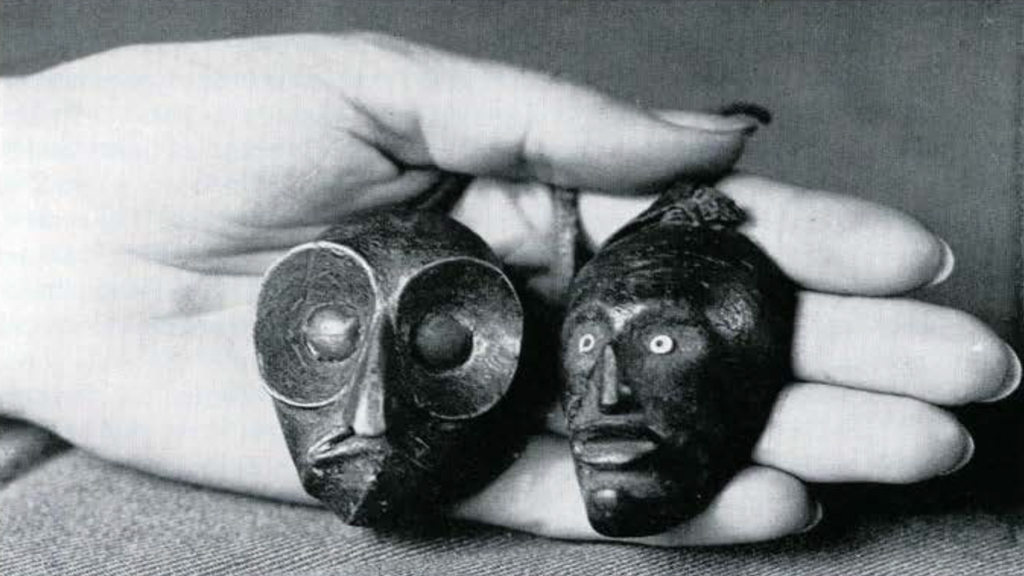 Two small wooden maskettes held in a hand