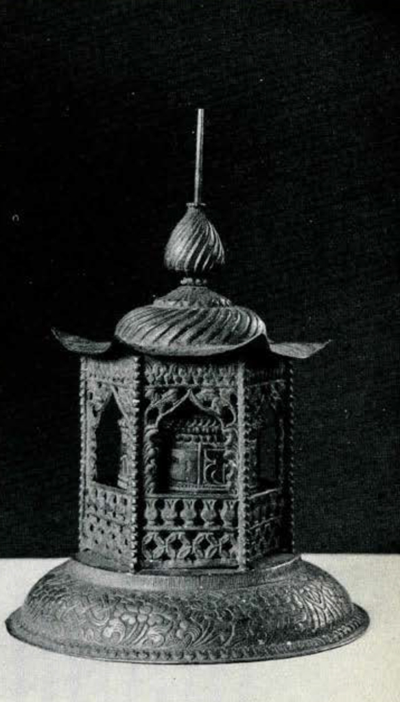 A prayer wheel in the shape of a house, the wheel can be viewed through the windows.