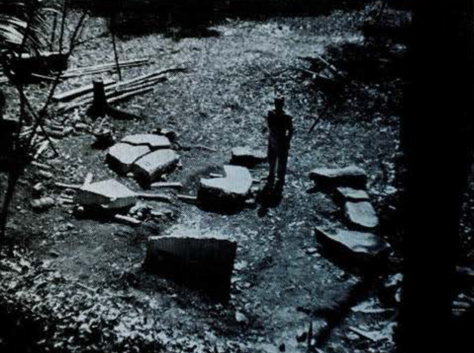 A person standing, surrounded by massive fragments of stone.