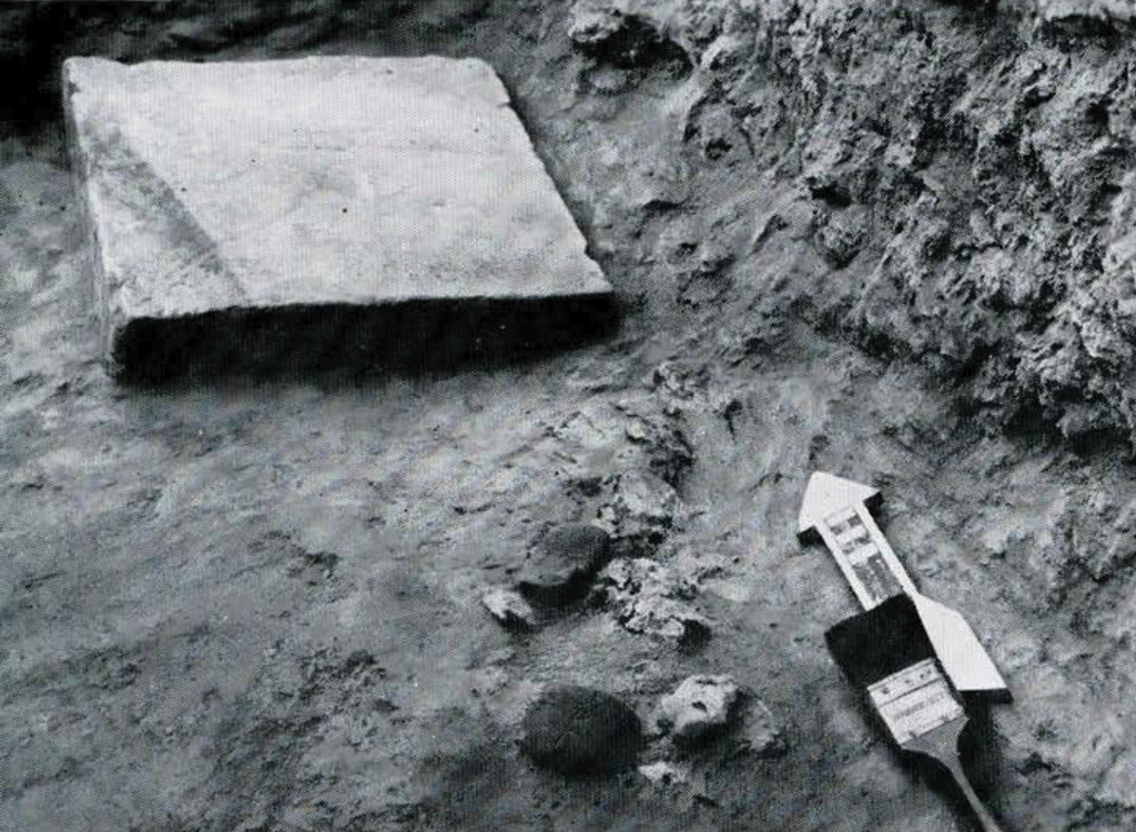 Tablets and bricks laying in the ground, excavation tools nearby.