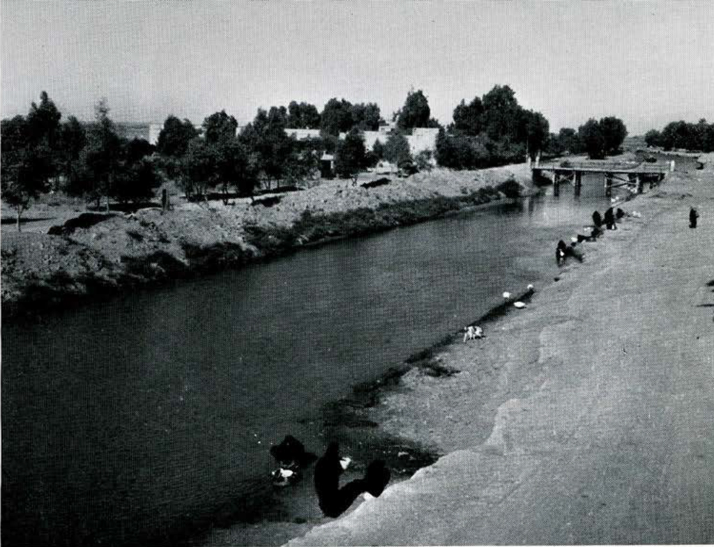 View of a canal with a bridge over it, people along the banks.