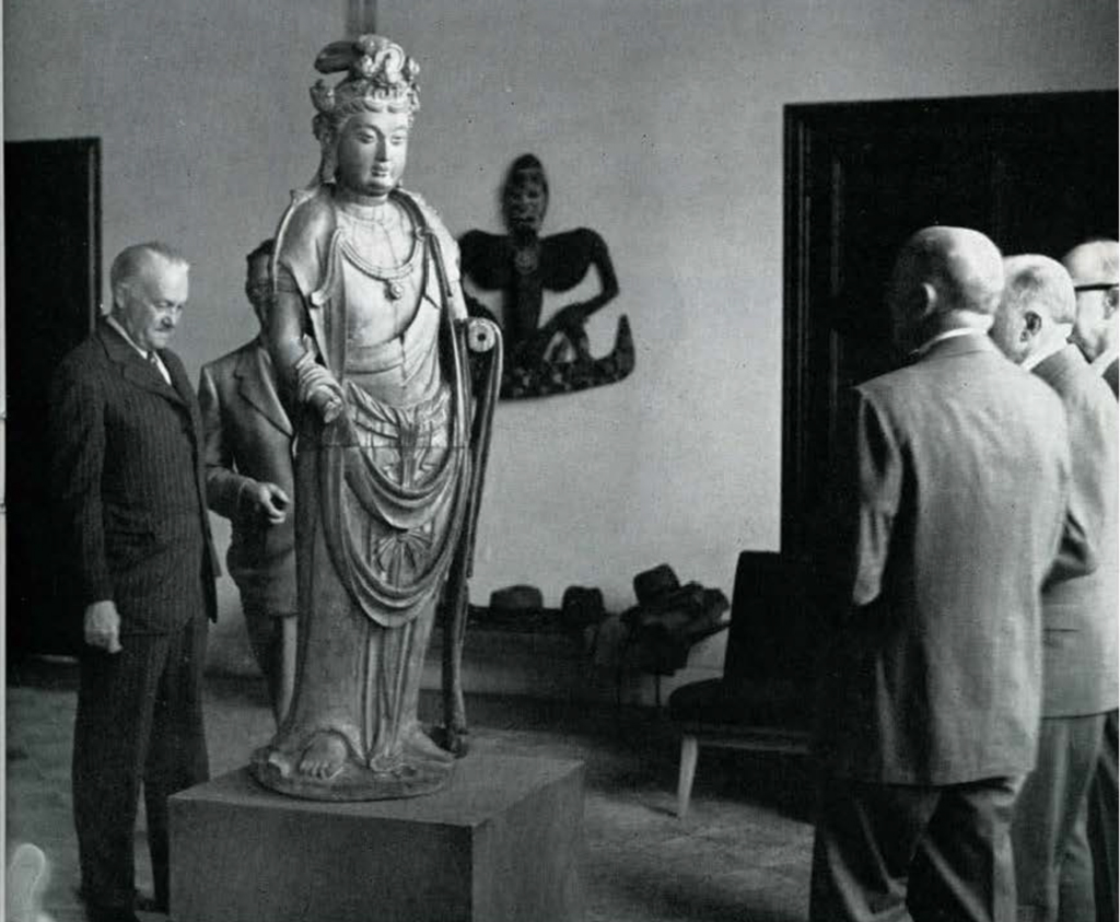 Men standing around a Chinese statue of Guanyin.