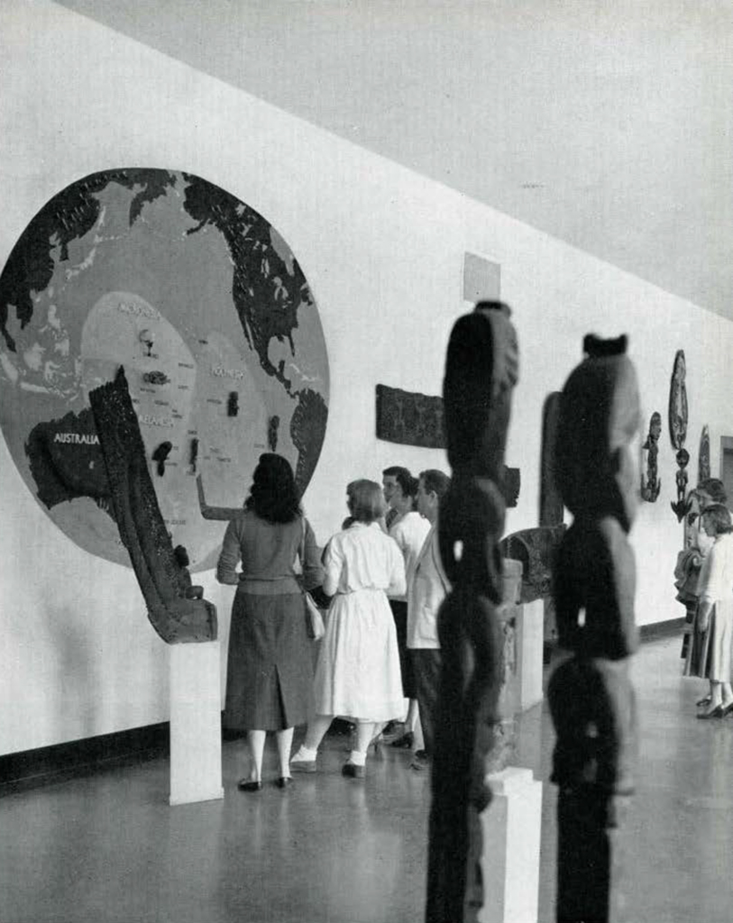 People examining a map of the Pacific Islands in a new gallery.