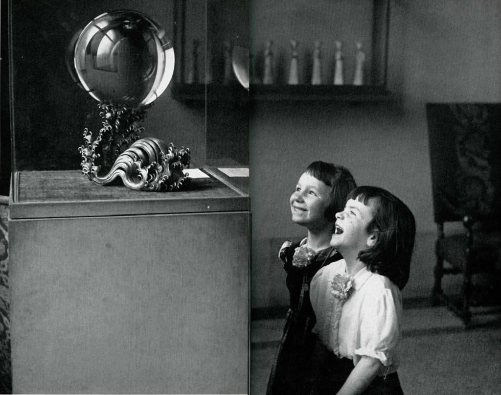 Two girls grinning at the large crystal ball.