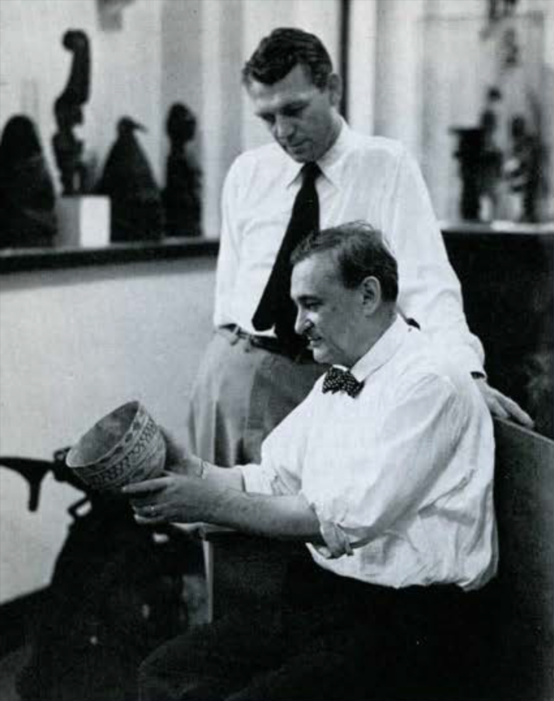 Two men examining a painted vase.
