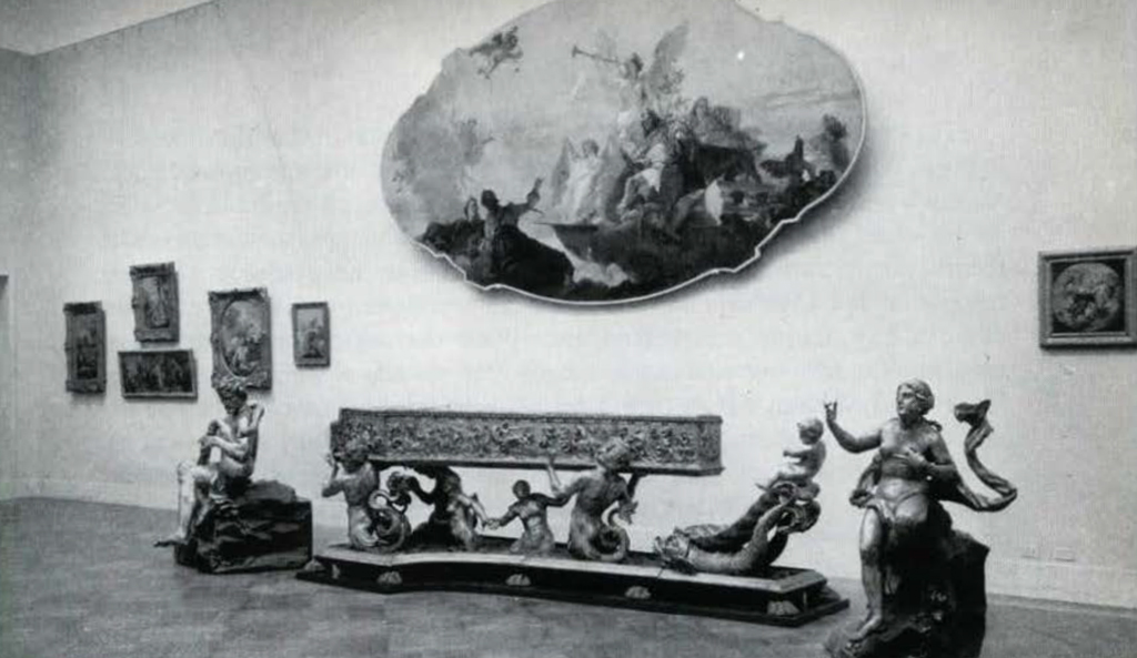 A gallery with paintings on hung on the wall and scultpures on the floor beneath.
