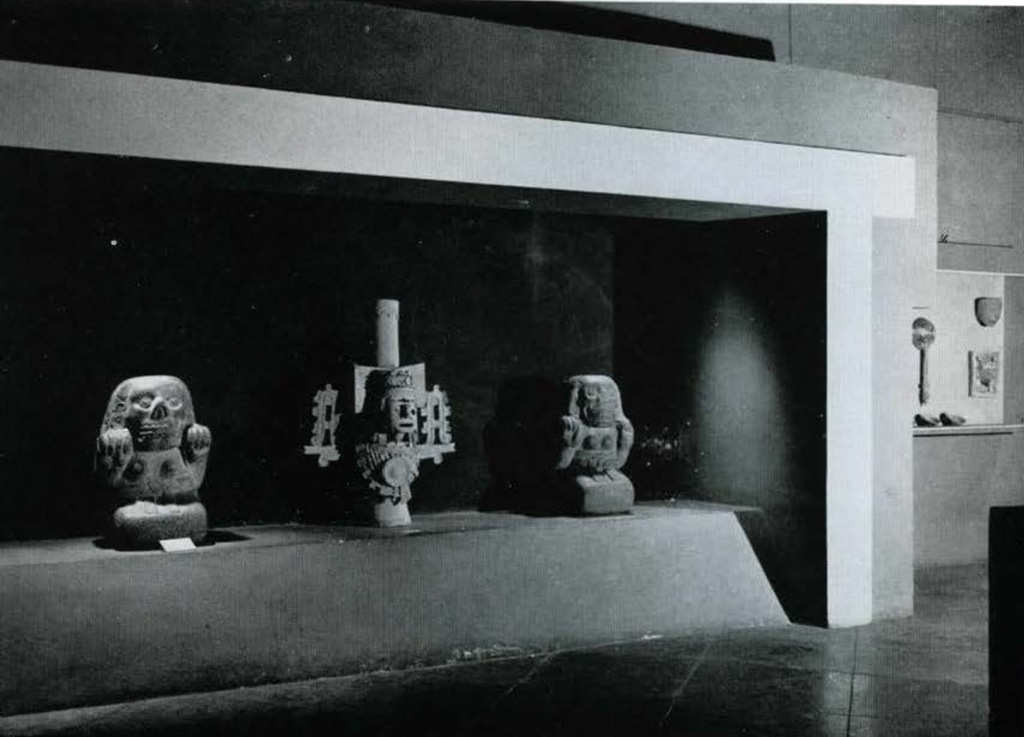 Three large stone scultpures of stylized people in a display.