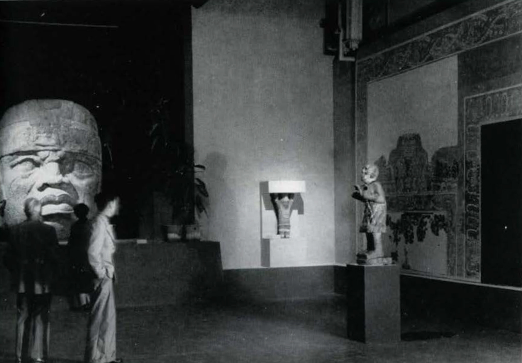 People in a gallery viewing a massive stone head.