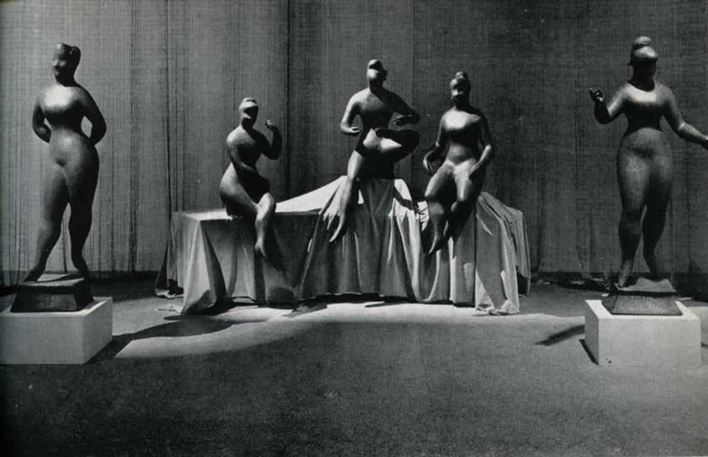 Five smooth statues of women in a gallery.