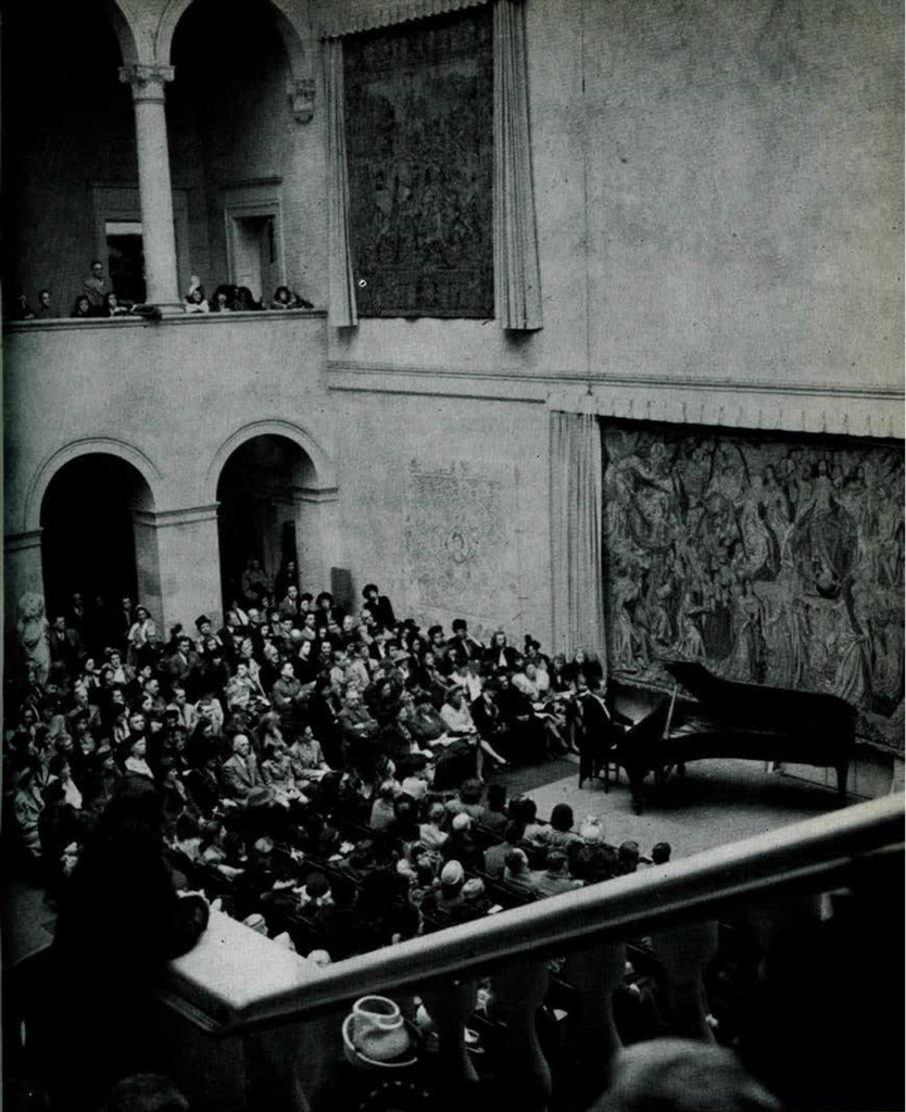 A concert hall full of people listening to a man play piano.