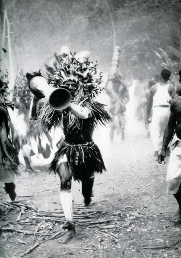 A man in full regalia, running with a drum.