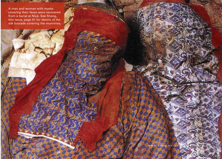Remains of a man and woman covered in colorfully patterned fabric, red scarves tied around their heads.