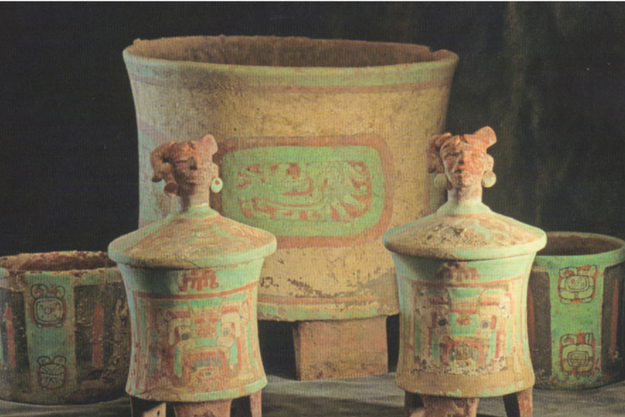 Five vessels of varying sizes with green Maya glyphs on the outside.