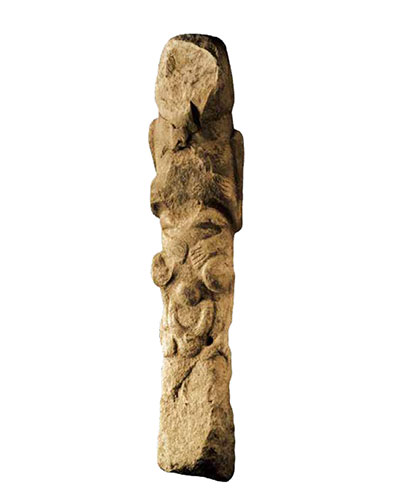 A totem pole, figures stacked atop each other carved into a stone pillar.