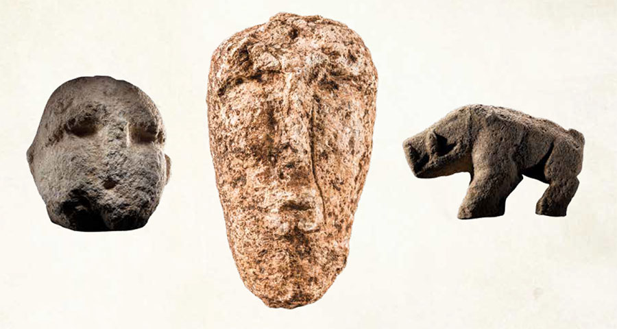 Two crude stone heads and a stone boar.